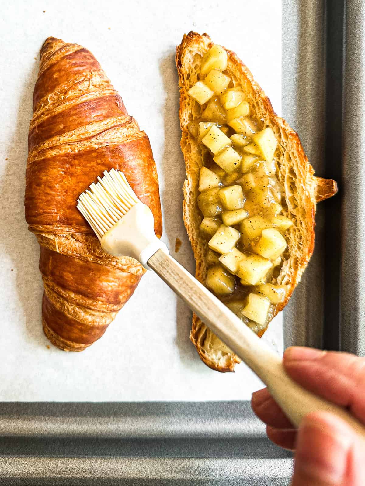Brushing top of croissant with egg wash.