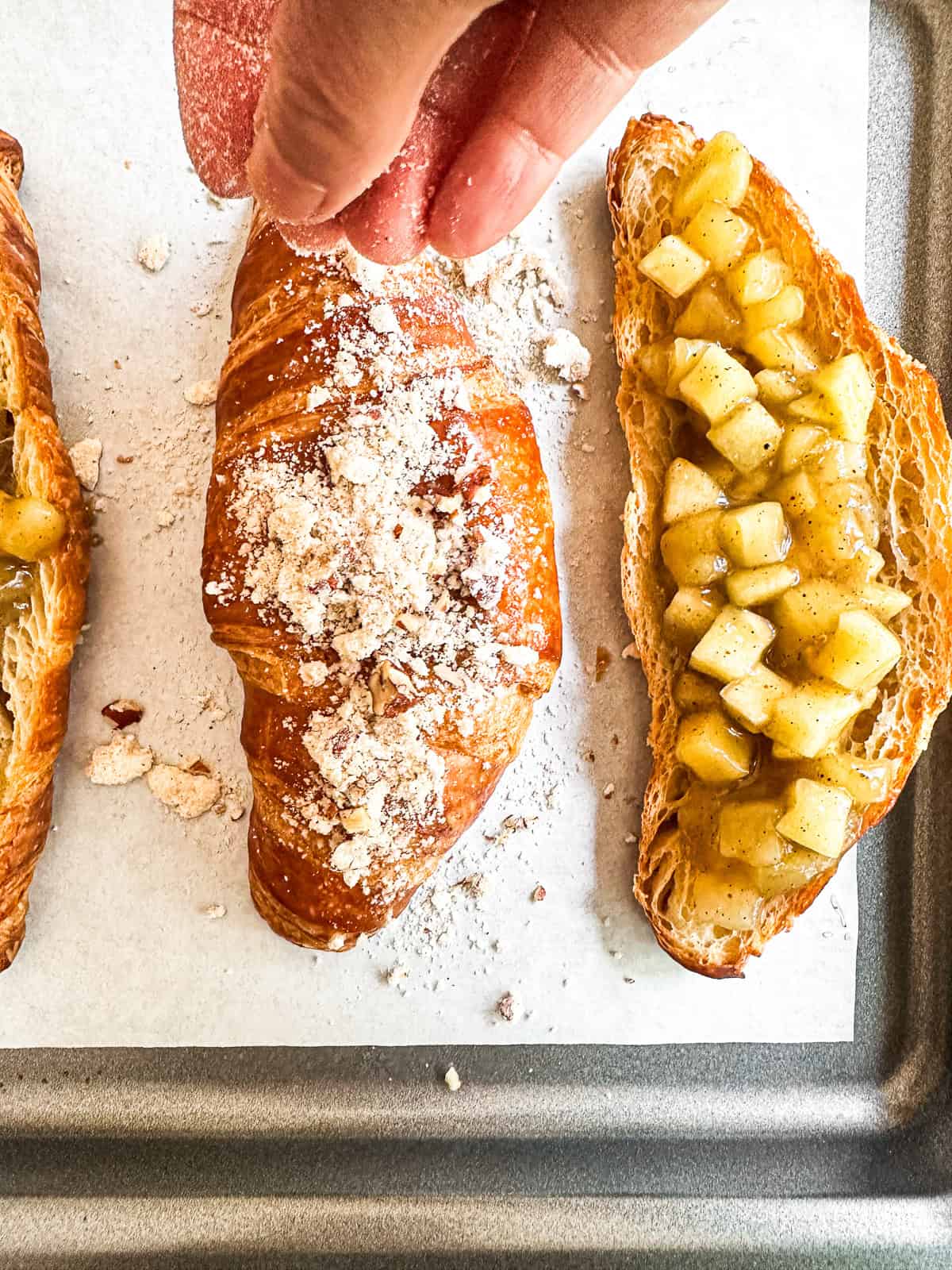 Dusting top of twice baked apple pie croissants with buttery pecan streusel.