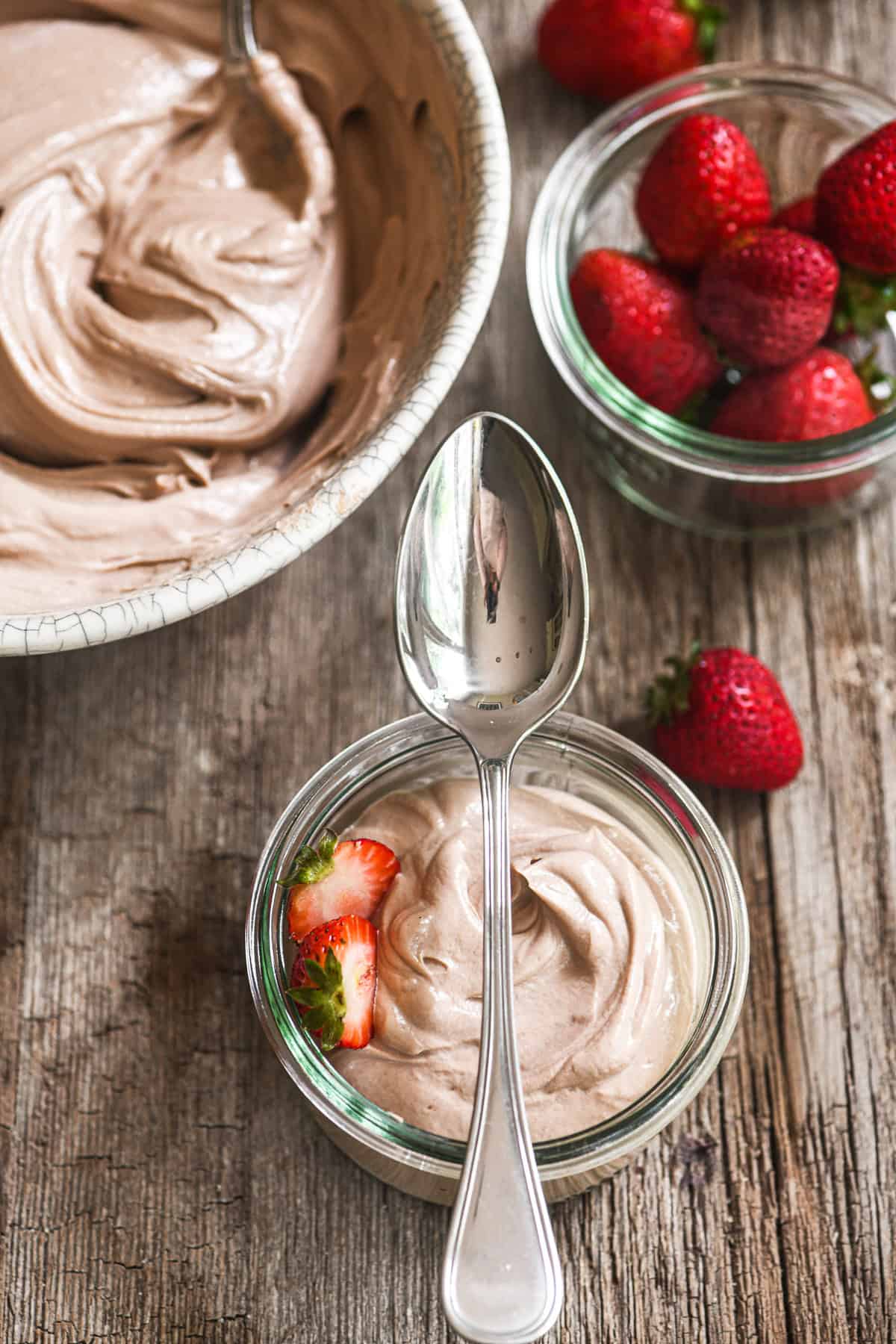 chocolate hazelnut yogurt in a small bowl with spoon, with strawberries.
