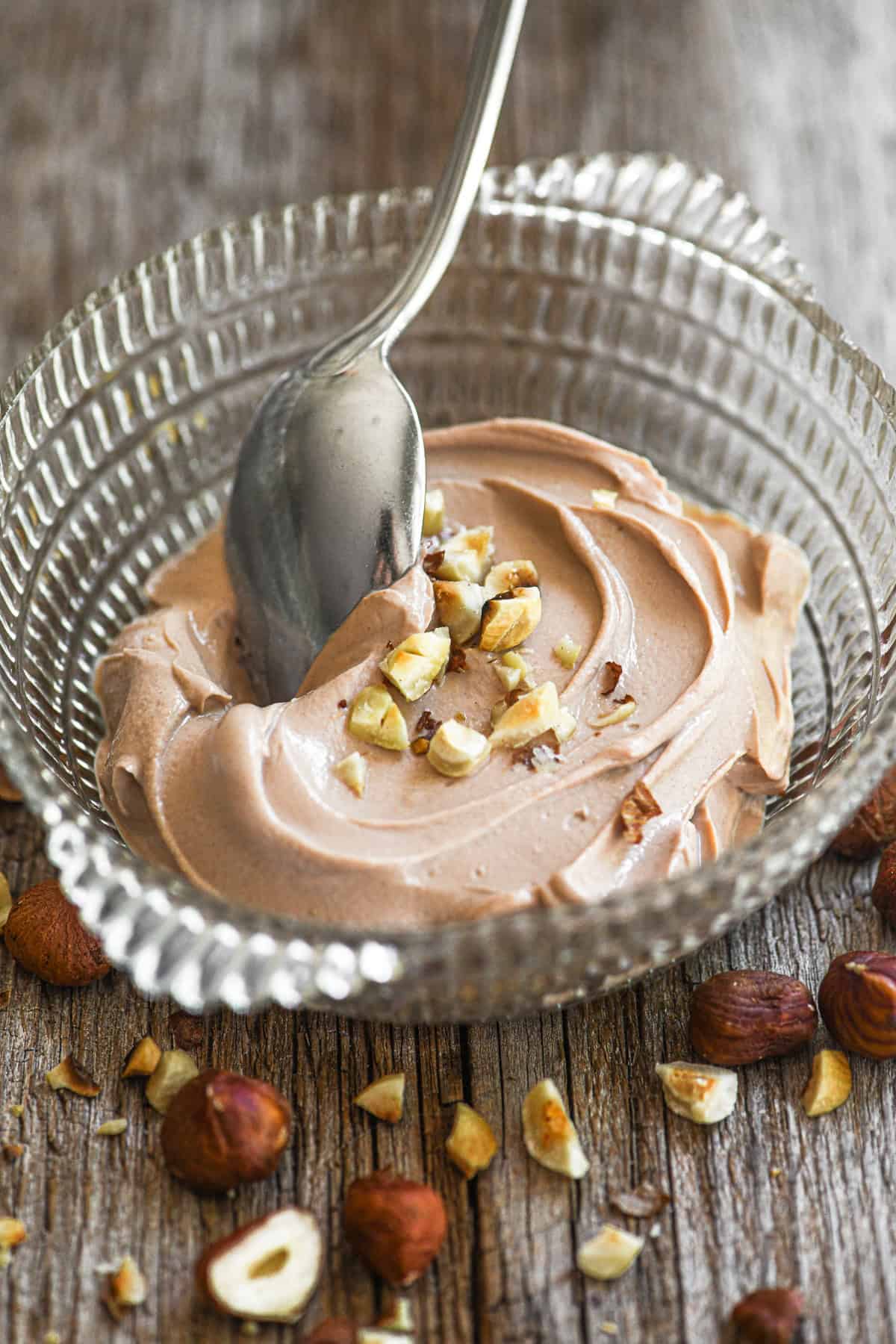 Chocolate hazelnut yogurt in a small dish topped with toasted chopped hazelnuts.