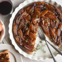Caramelized shallot tarte tatin in a white pan with slice removed.