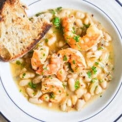 Lemony shrimp and white beans in a bowl with crusty bread.
