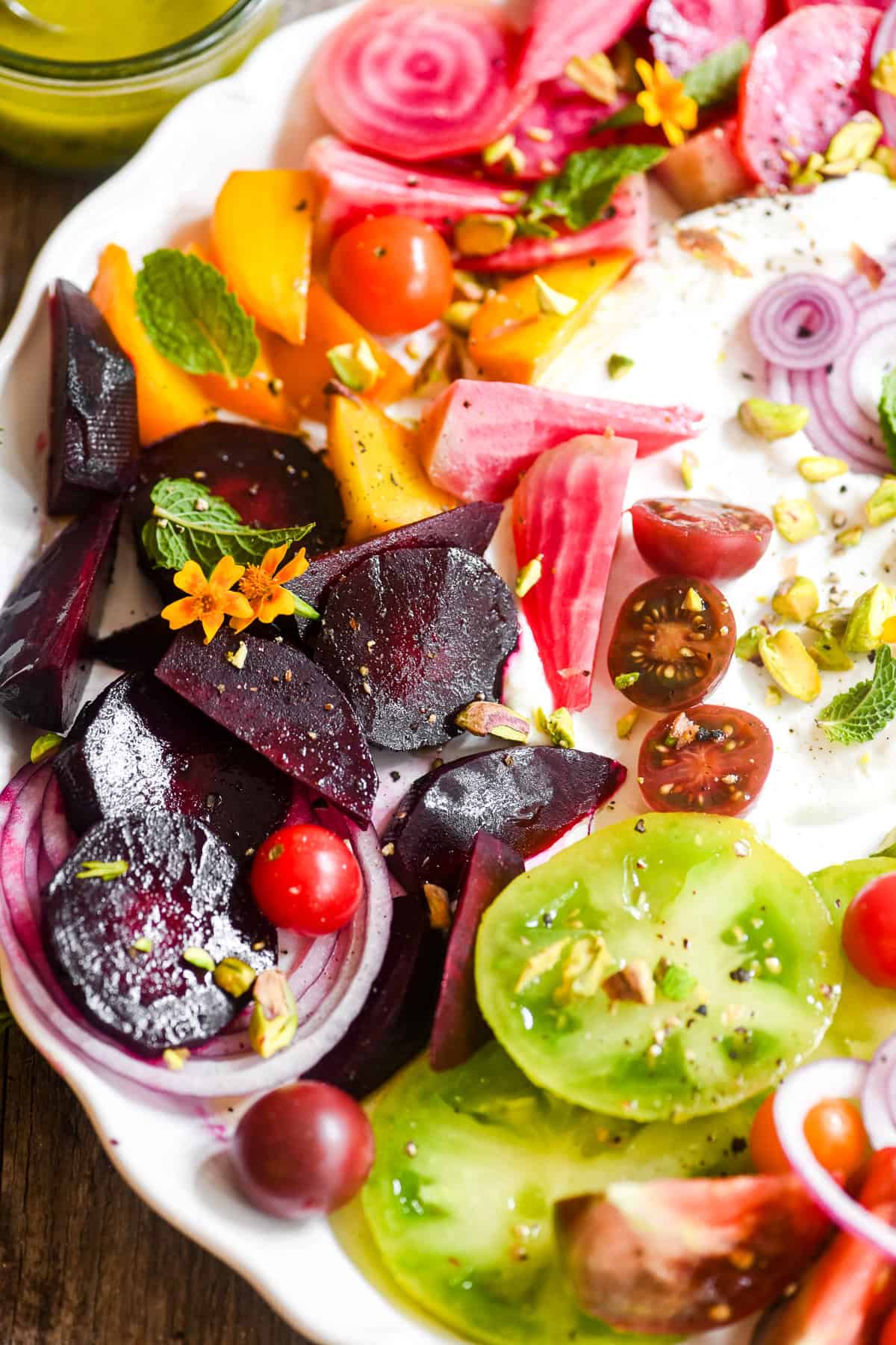 tomato and beet salad with whipped goat cheese on a white platter.