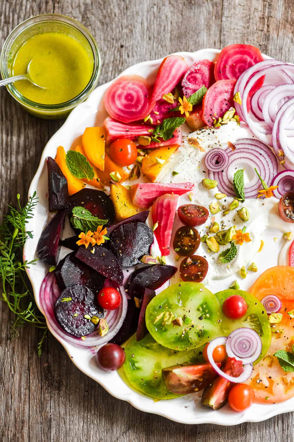 A pretty tomato and beet salad on a platter with whipped goat cheese.