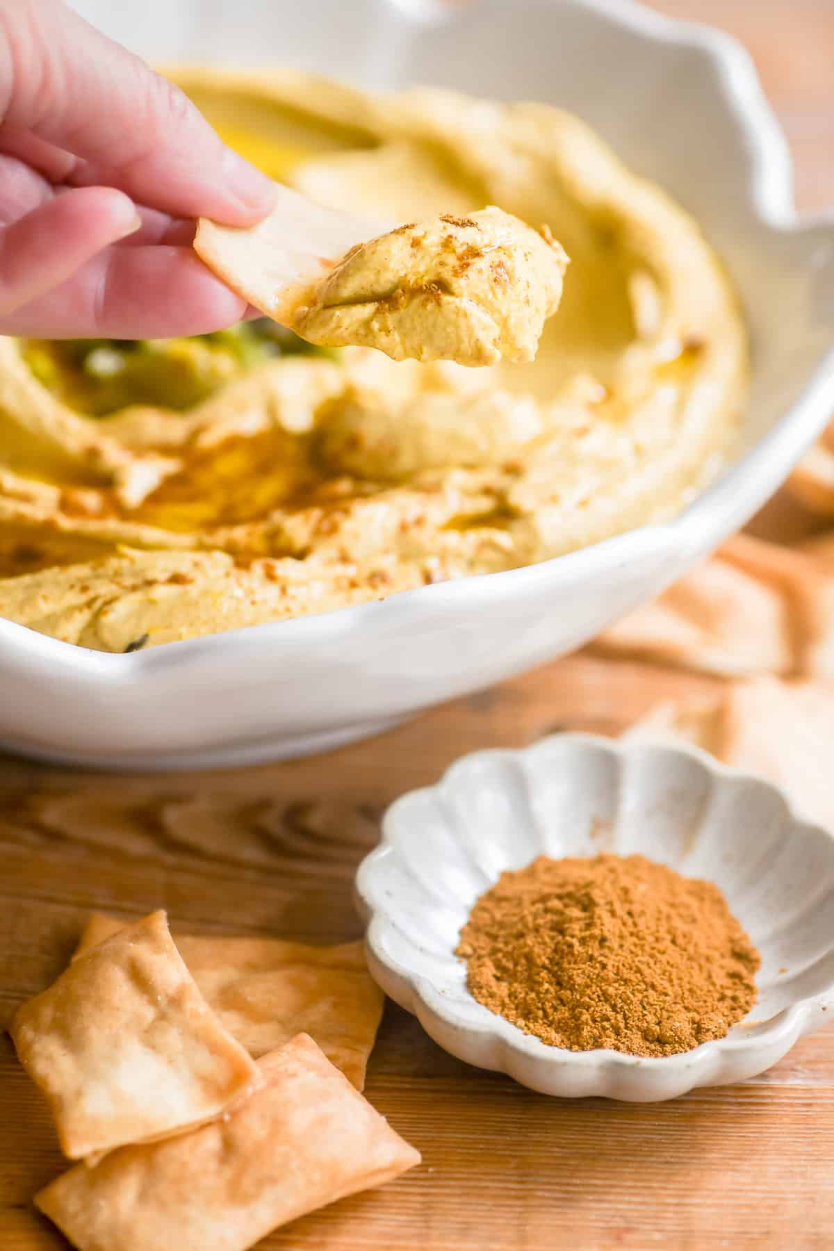 Scooping Moroccan hummus with a pita chip.
