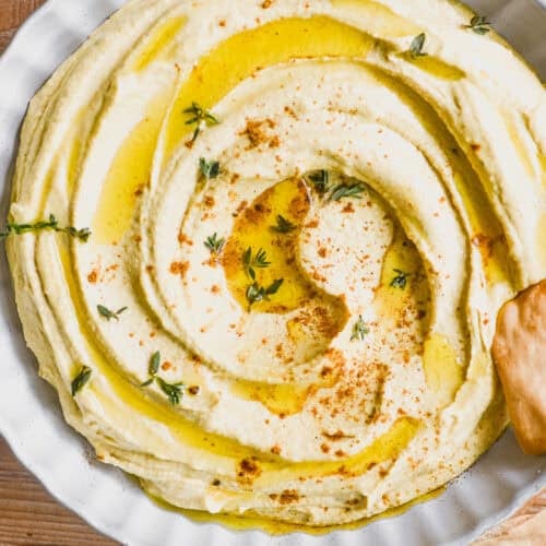 overhead look at a bowl of Moroccan hummus topped with a dusting of ras el hanout.