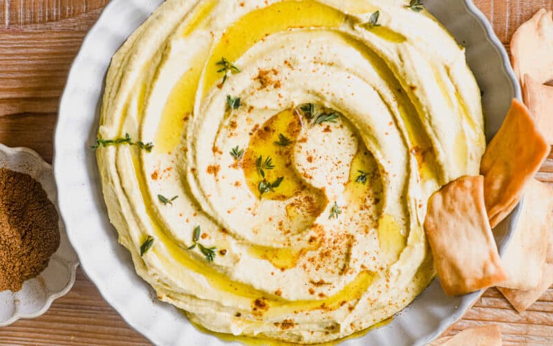 overhead look at a bowl of Moroccan hummus topped with a dusting of ras el hanout.