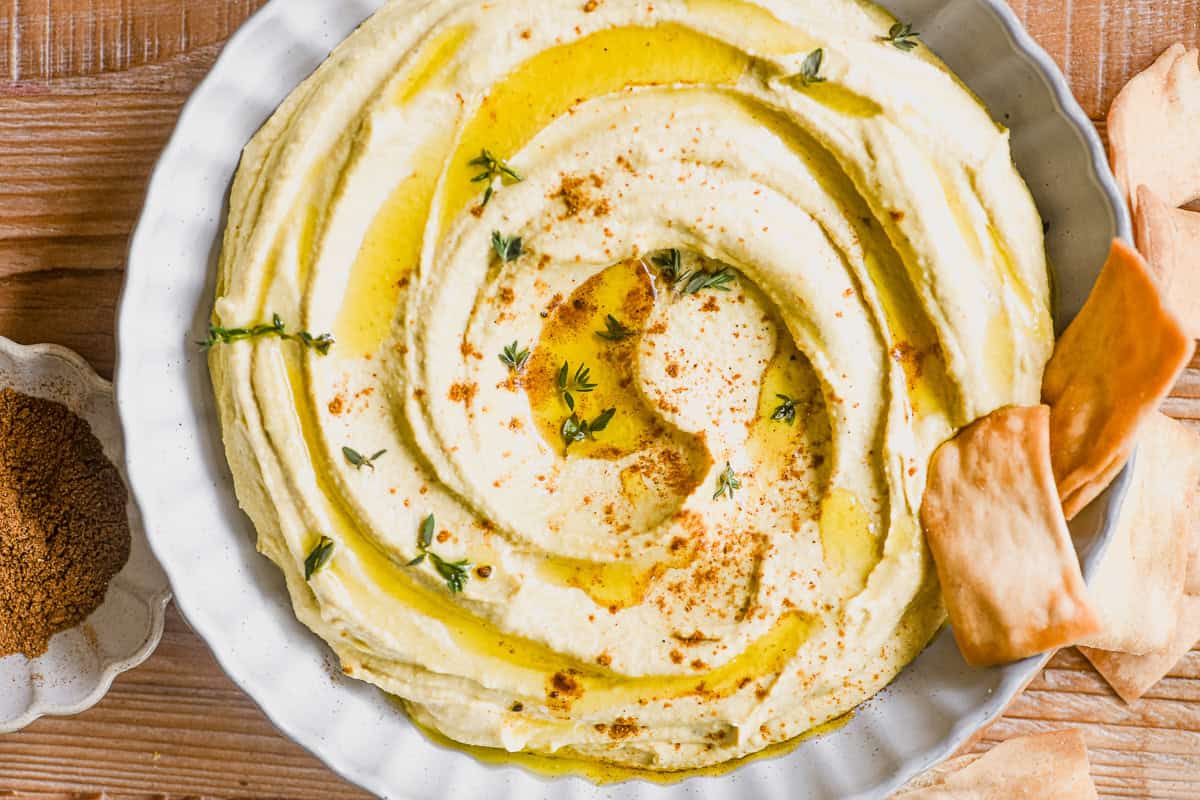 overhead look at a bowl of Moroccan hummus topped with a dusting of ras el hanout.