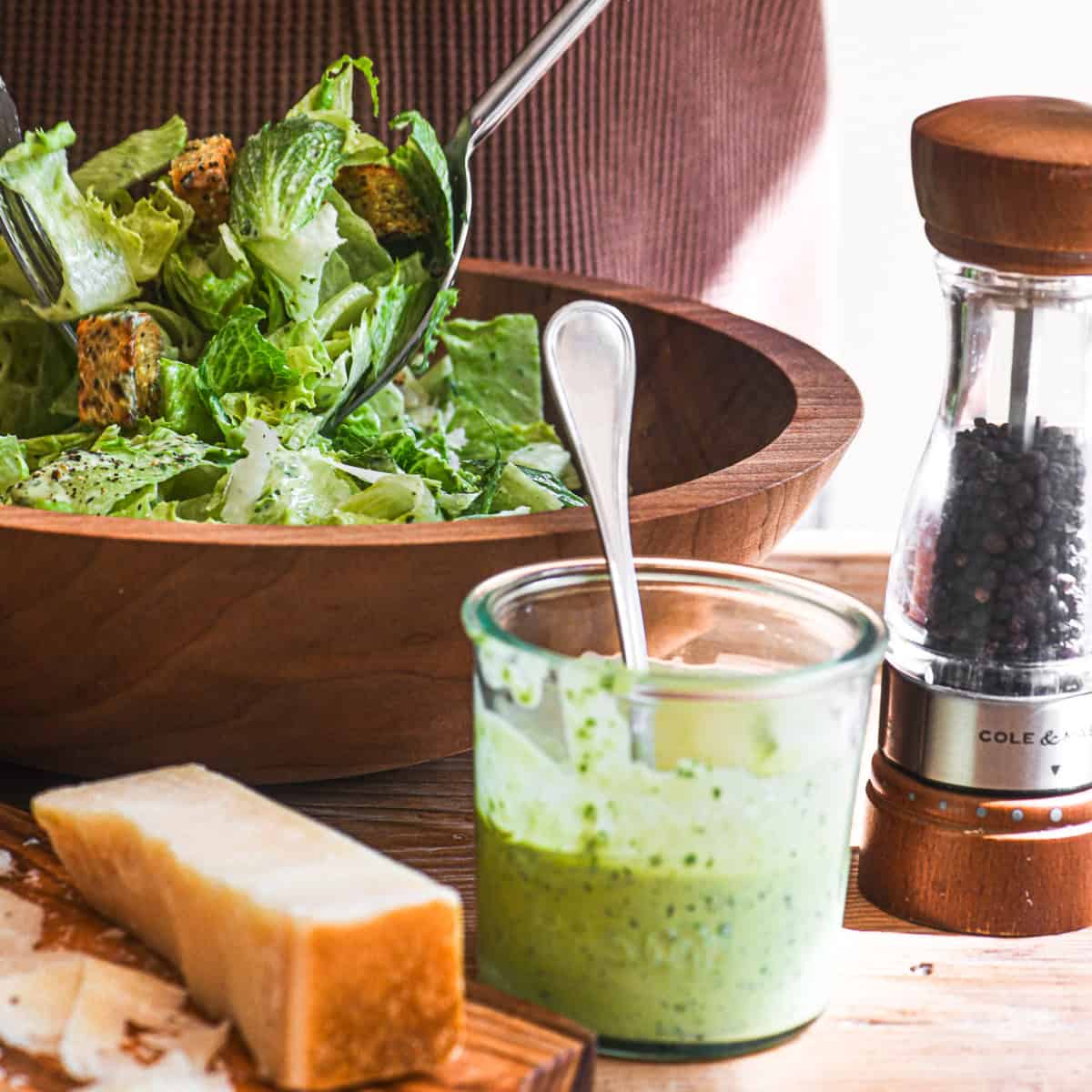 tossing a caesar salad with basil caesar salad dressing.