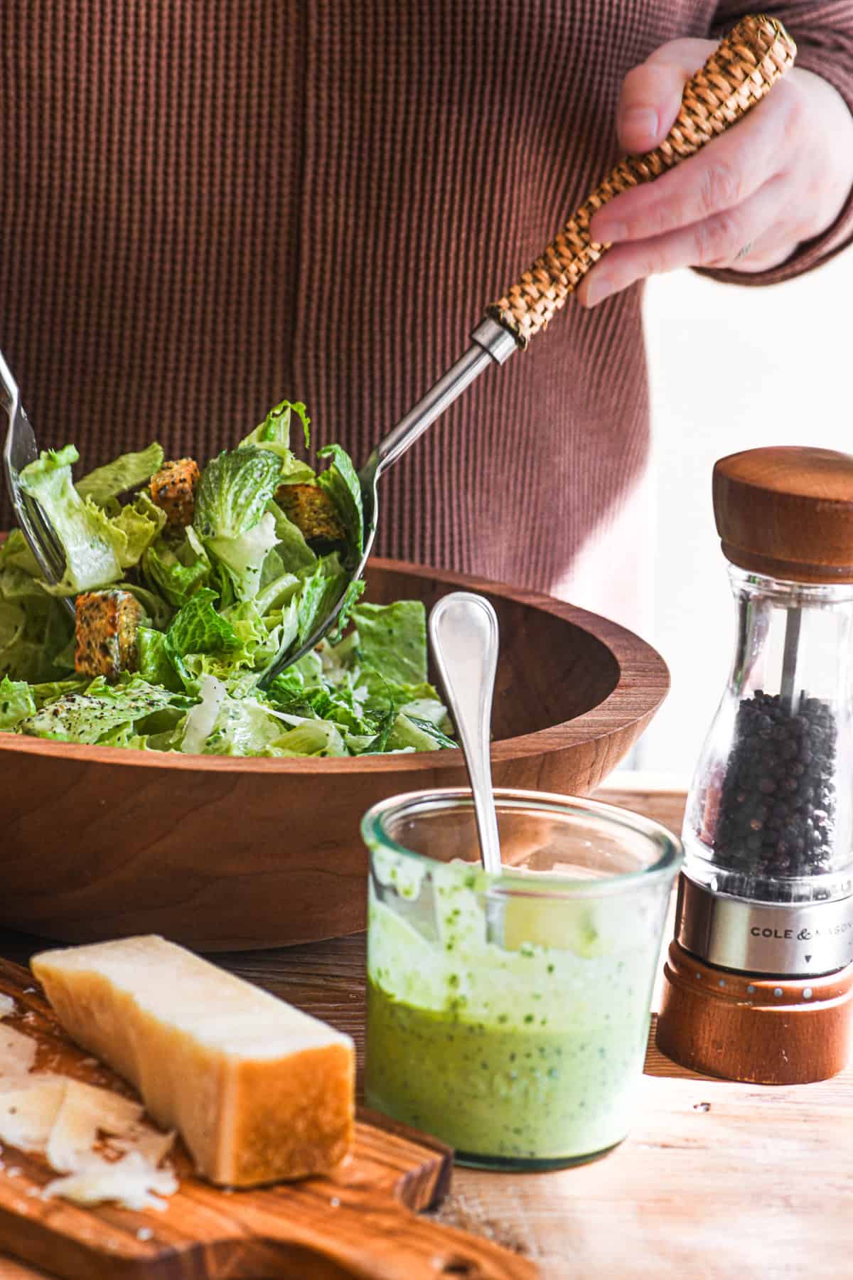 Tossing a Caesar salad with pesto Caesar salad dressing.