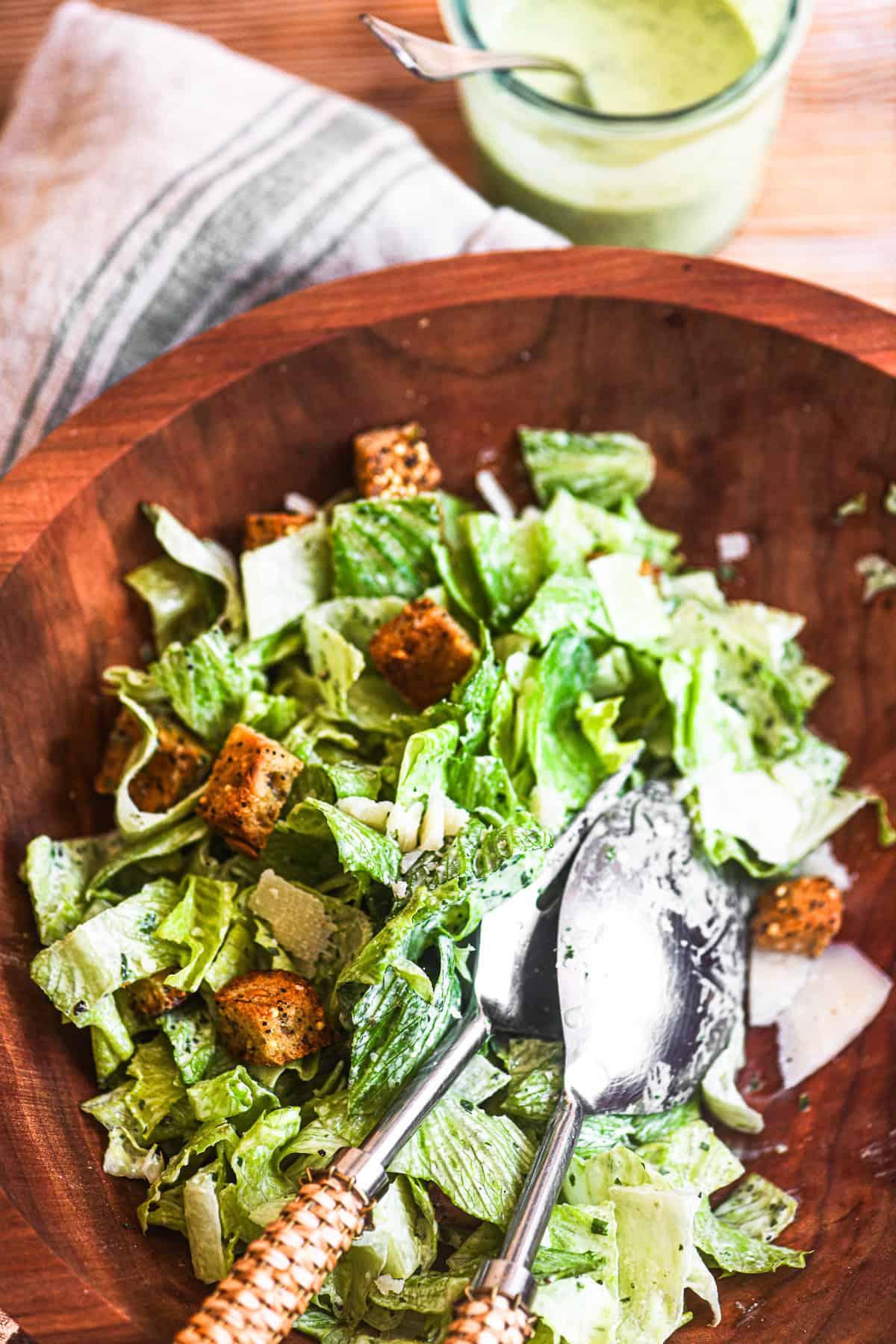 Salad with pesto Caesar dressing, in a wooden salad bowl.
