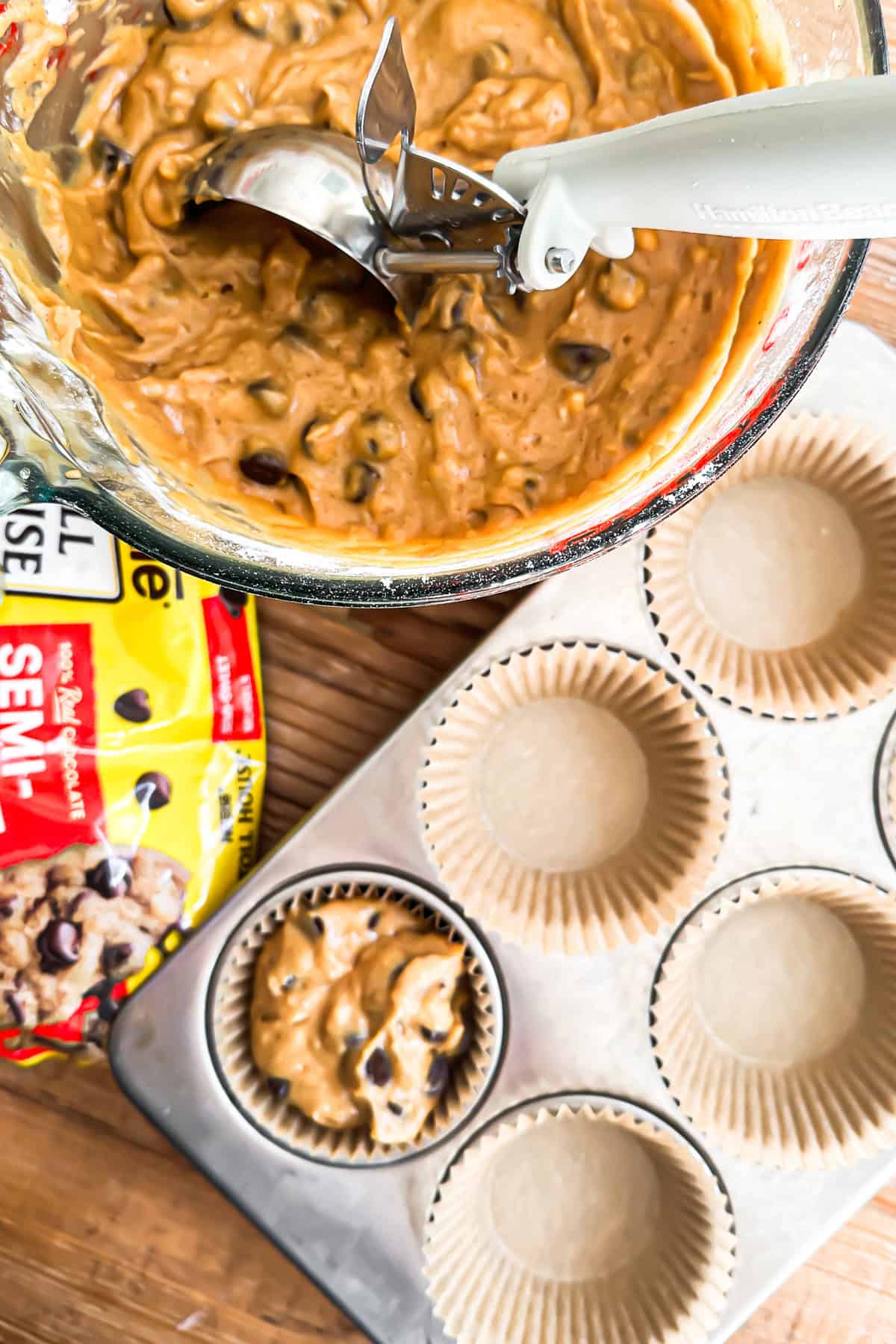 Scooping chocolate chip pumpkin muffins into a muffin pan.