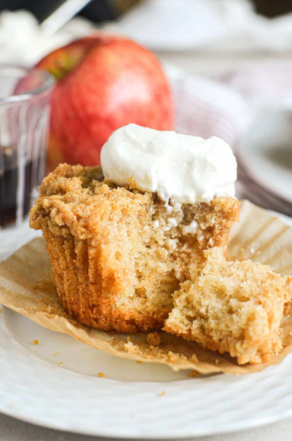 Mini apple crumb cake with bite taken, topped with whipped cream.