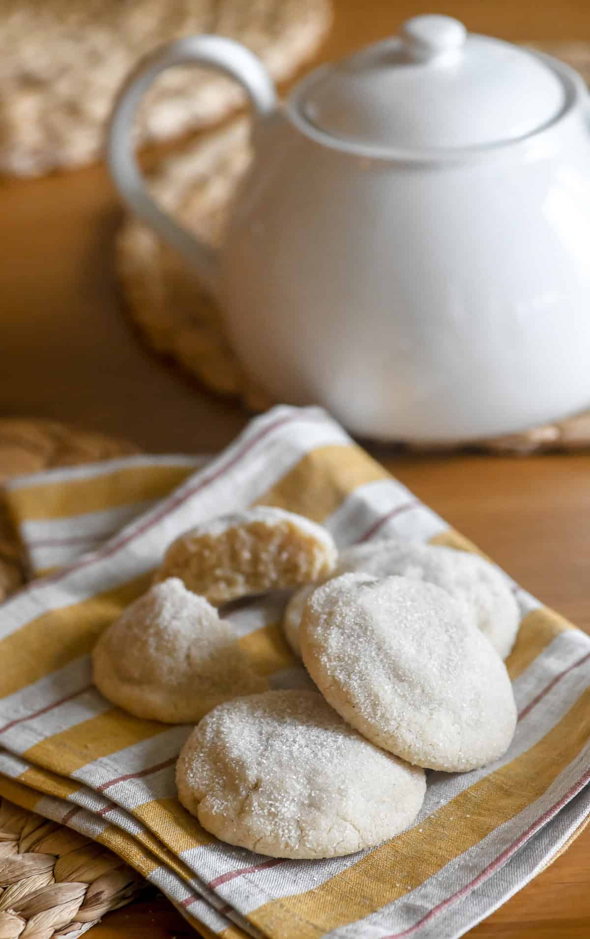 Swedish almond cardamom cookies on a napkin with tea pot.