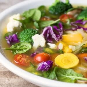 Detox vegetable soup in a white bowl with spoon.