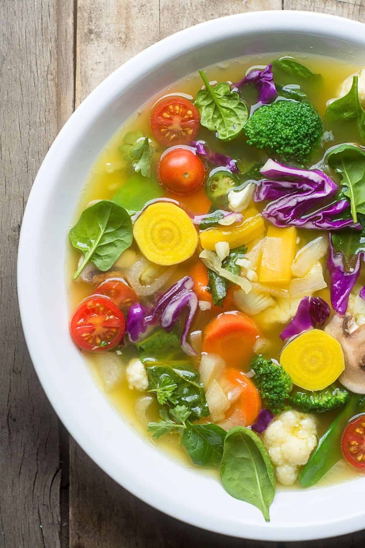 Colorful slimming detox veggie soup on a white bowl.